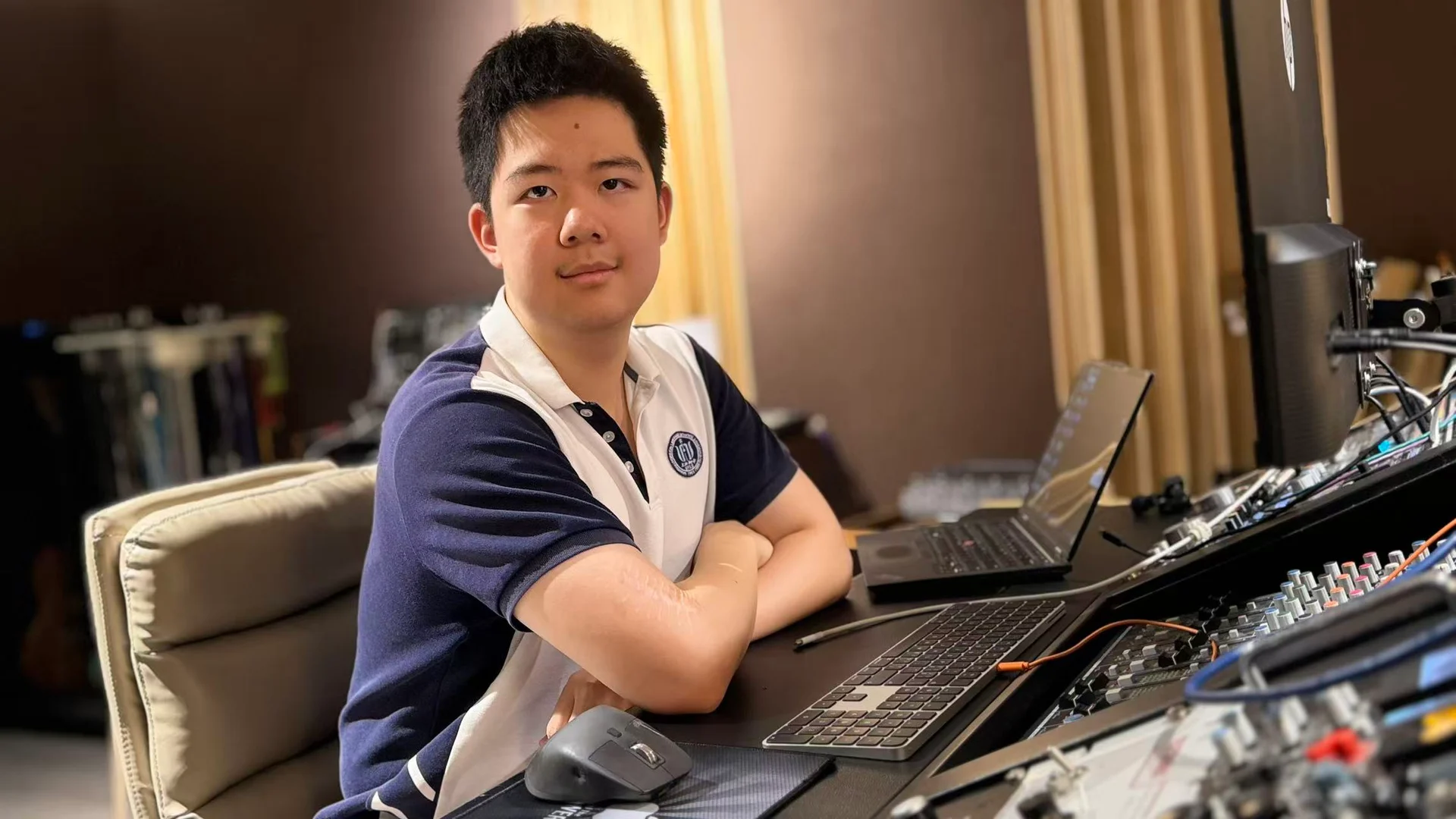 Shuran at his workstation, with a computer, keyboard, and music equipment